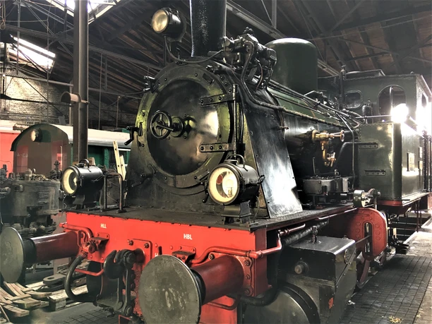 Dampflok im Eisenbahnmuseum <img alt="Historische Dampflokomotive im Lokschuppen mit roten und schwarzen Anstrichen" />