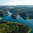 Genkeltalsperre <p>Luftaufnahme eines üppigen, grünen Waldes durchzogen von einem ruhigen, blauen Fluss, sanfte Hügel im Hintergrund.</p>