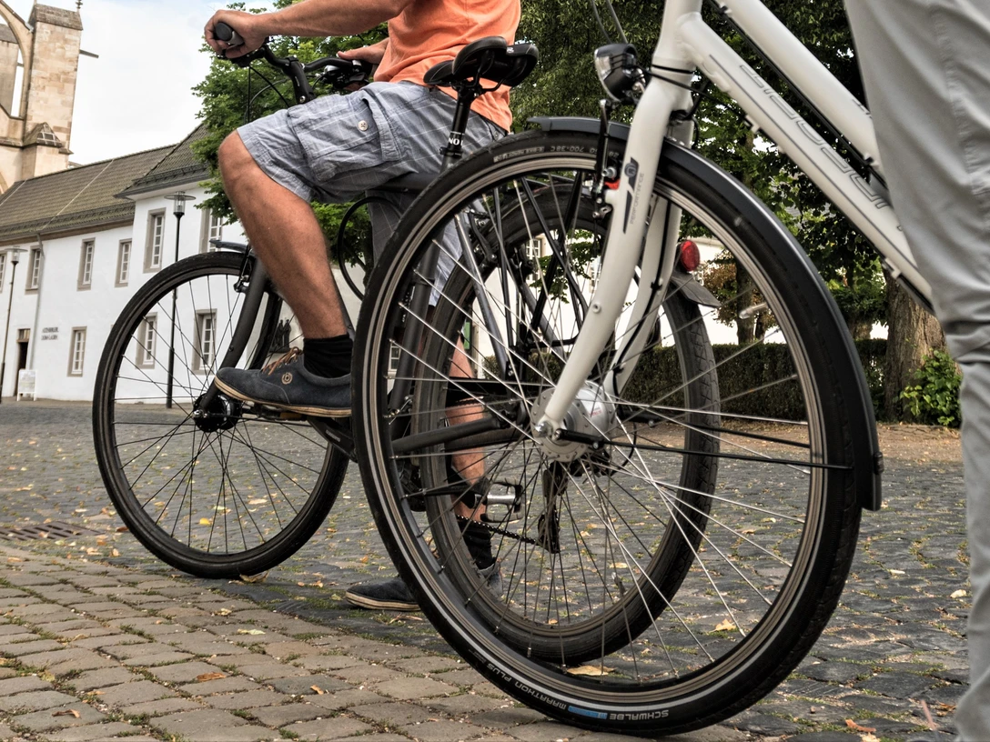Rad fahren in Altenberg Zwei Personen auf Fahrrädern fahren auf einem gepflasterten Weg vor einem historischen Gebäude.