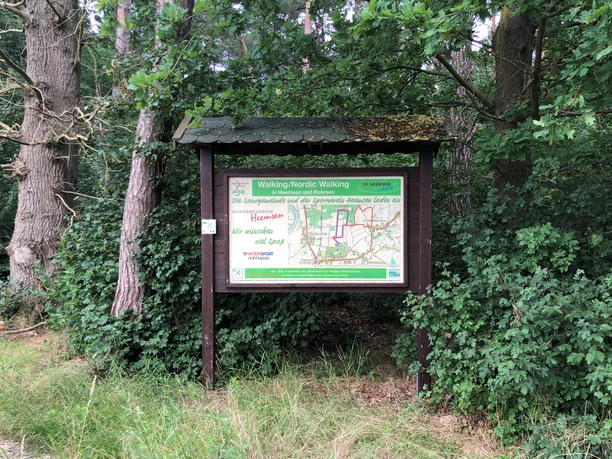 Een houten informatiebord aan de rand van het bos met een routeoverzicht voor nordic walking in Heemsen.