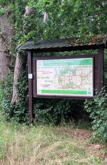 Eine Informationstafel in einem bewaldeten Gebiet informiert über Nordic Walking Routen in Heemsen.