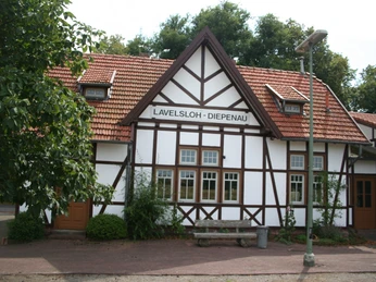Historisch anmutendes Fachwerkgebäude des Hochzeitsbahnhofs Lavelsloh umgeben von grüner Natur.