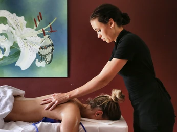 Massage im Gräflichen Park Eine Masseurin massiert den Rücken einer liegenden Frau in einem stilvoll dekorierten Raum.