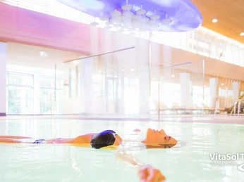 VitaSol Therme - Intensivsolebecken Person in einem Hallenbad treibt entspannt auf dem Rücken im hell beleuchteten, modernen Solebecken.