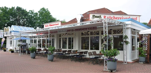 smoortaal-aussenansicht.jpg Das Bild zeigt die Außenterrasse eines Restaurants mit Sitzgelegenheiten und Blumenarrangements.