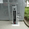 Fahrrad-Luftstation am Achimer Bahnhof mit integrierter Pumpe, umgeben von Metallgitter und Pflanzen.