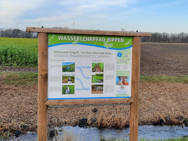 Radwasserlehrpfad Houten planken op het Bippen waternatuurpad met windturbines op de achtergrond.