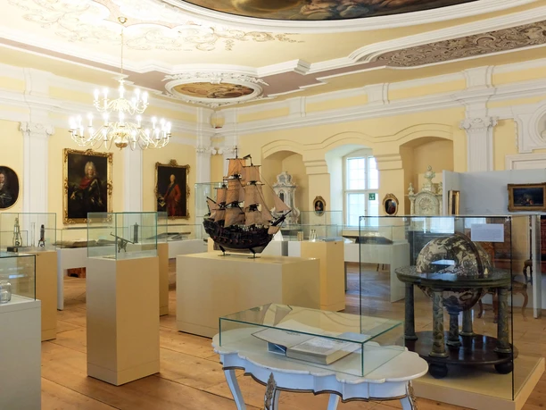 OL_Zittau_Stadtmuseum_WG_DSCF4127.JPG Innenraum eines Museums mit historischen Schiffsmodellen und Gemälden unter einer verzierten Decke.