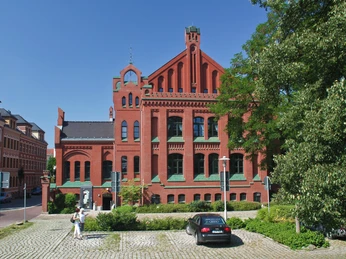 Zwickau - Johannisbad-03-© mattrose.de.jpg Backsteingebäude des Johannisbads in Zwickau, umgeben von Bäumen und Parkplatz.Brick building of the Johannisbad in Zwickau, surrounded by trees and a parking lot.Cihlová budova Johannisbad ve Zwickau, obklopená stromy a parkovištěm.Ceglany budynek Johannisbad w Zwickau, otoczony drzewami i parkingiem.Bakstenen gebouw van het Johannisbad in Zwickau, omgeven door bomen en een parkeerplaats.Edificio in mattoni del Johannisbad di Zwickau, circondato da alberi e da un parcheggio.