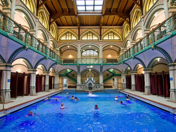 Zwickau - Johannisbad-08-(c)mattrose.de.jpg Personen schwimmen im historischen Innenpool des Johannisbads Zwickau unter malerischen Arkaden.