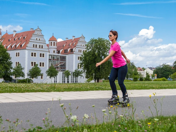 021 - Zwickau - Muldeparadies, Schloss Osterstein - © Kultour Z.jpg Eine Frau rollt auf Inlineskates auf einem Weg, vor dem Schloss Osterstein.