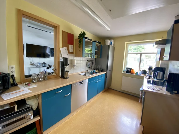 image00005.jpeg Helle Küche mit blauen Schränken, viel Tageslicht und modernen Geräten ausgestattet.