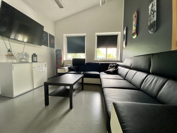 image00009.jpeg Ein heller Raum mit schwarzen Sofas und Tisch. Kunstwerke und ein TV schmücken die Wände.