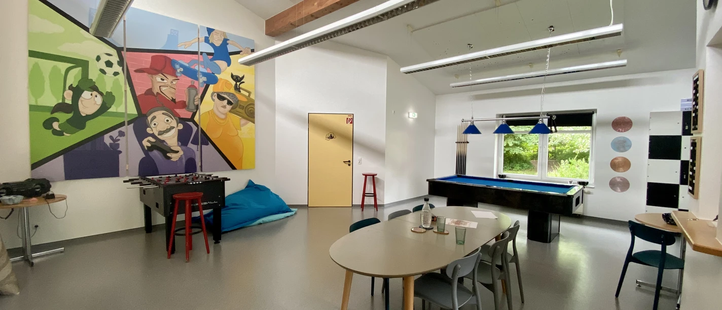 CASA Jugendraum Der Jugendraum "CASA" ist ein heller Raum mit bunten Wänden. Er hat einen Tischkicker und einen Billardtisch.