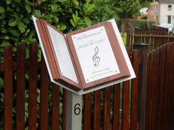 Straße der Lieder Marklohe Ein Schild aus Holz mit Notenschlüssel begrüßt an der "Straße der Lieder" in Marklohe.