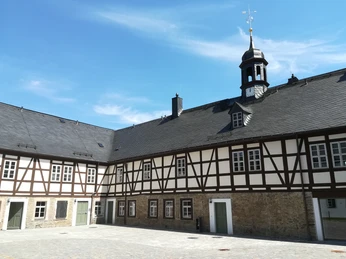 Innenhof Herrenhof Erlahammer Schwarzenberg-Welterbe_erleben (Foto Stadtverwaltung Schwarzenberg).jpg Innenhof mit Fachwerkgebäuden und Spitzdach unter blauem Himmel im Herrenhof Erlahammer.Inner courtyard with half-timbered buildings and pointed roof under a blue sky in the Erlahammer manor house.Vnitřní nádvoří s hrázděnými budovami a špičatou střechou pod modrou oblohou na zámku Erlahammer.Wewnętrzny dziedziniec z budynkami z muru pruskiego i spiczastym dachem pod błękitnym niebem w posiadłości Erlahammer.Binnenplaats met vakwerk en puntdak onder een blauwe hemel in het landhuis Erlahammer.Cortile interno con edifici a graticcio e tetto a punta sotto un cielo azzurro nel maniero di Erlahammer.