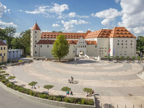 Freiberg_Schloss Freudenstein im Zentrum der historischen Freiberger Altstadt (c) ReneJungnickel_Schloss_02.jpg Schloss Freudenstein, ein Renaissancebau mit rotem Dach, umgeben von einem weitläufigen Platz.