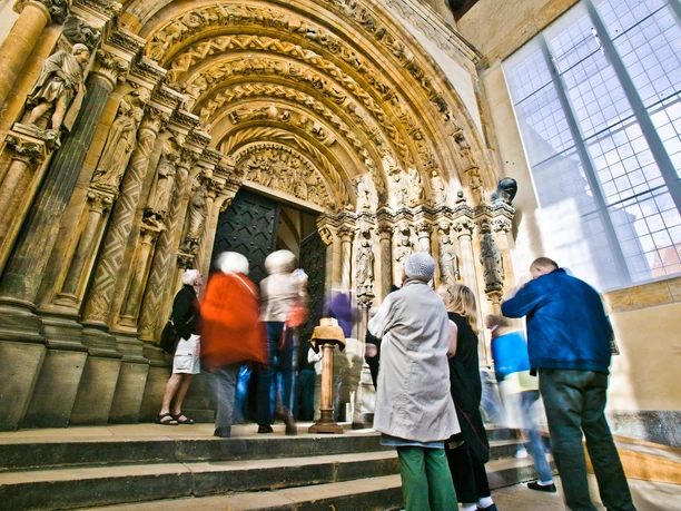 Group of visitors looking at the Gothically decorated Golden Gate in Freiberg Cathedral.