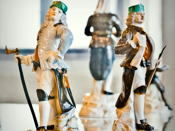 StadtFreiberg_FotografRalfMenzel_Museum_04.jpg Keramikfiguren in barocker Kleidung mit grünen Hüten, die historische Bergleute darstellen.