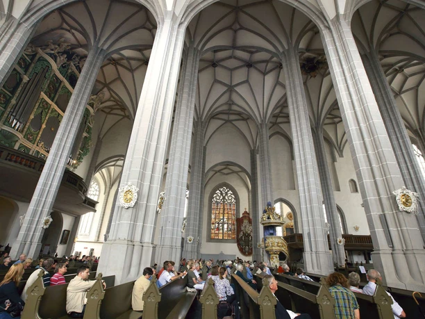 Interior view of St. Peter's Church in Görlitz with high Gothic vaults and visitors in pews.