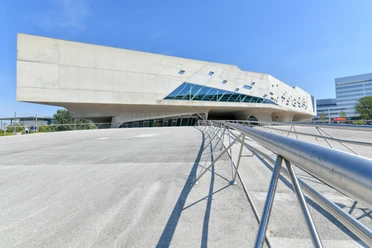 phaeno Außenansicht Modernes Betongebäude mit futuristischer Form und schrägen Glasflächen unter blauem Himmel.