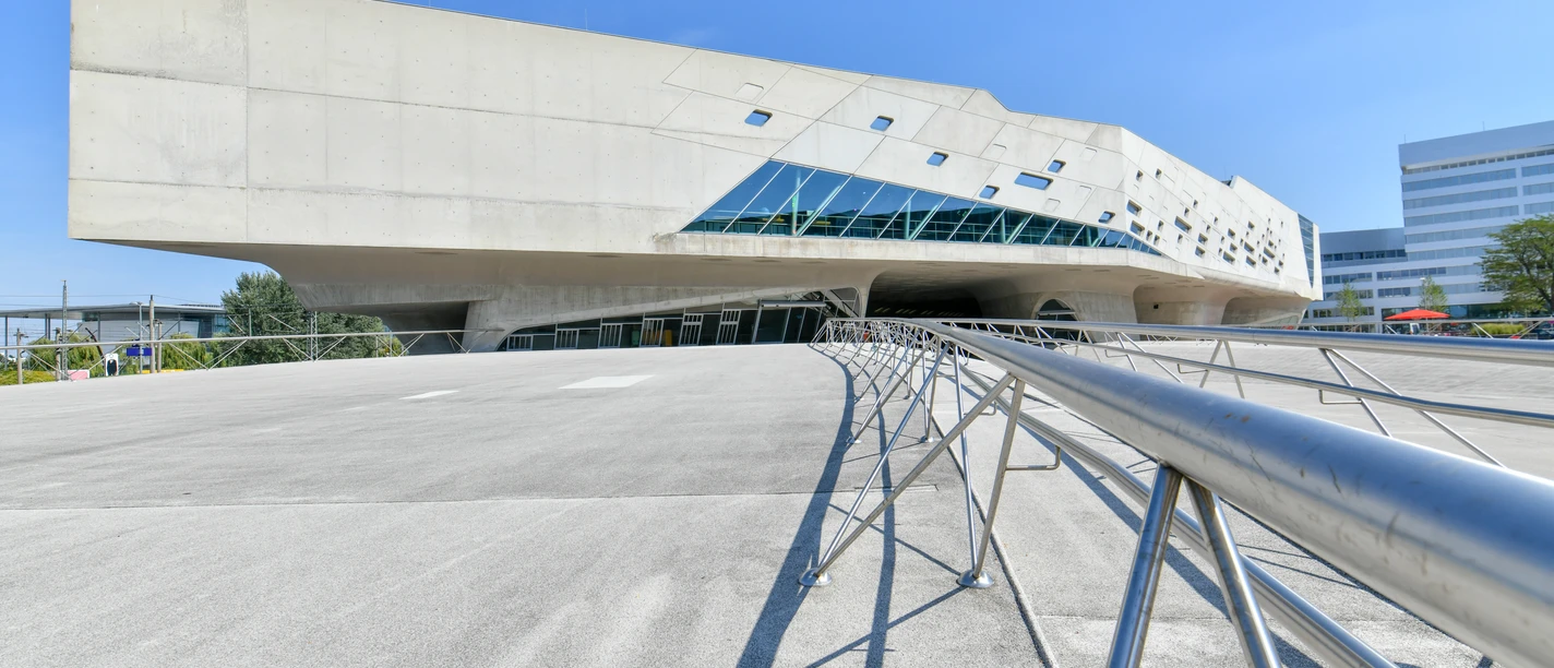 phaeno Außenansicht Modernes Betongebäude mit futuristischer Form und schrägen Glasflächen unter blauem Himmel.
