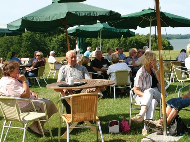 Frucht Café bei Lödings Bauernhof Menschen sitzen an Tischen auf Wiese mit Schirmen