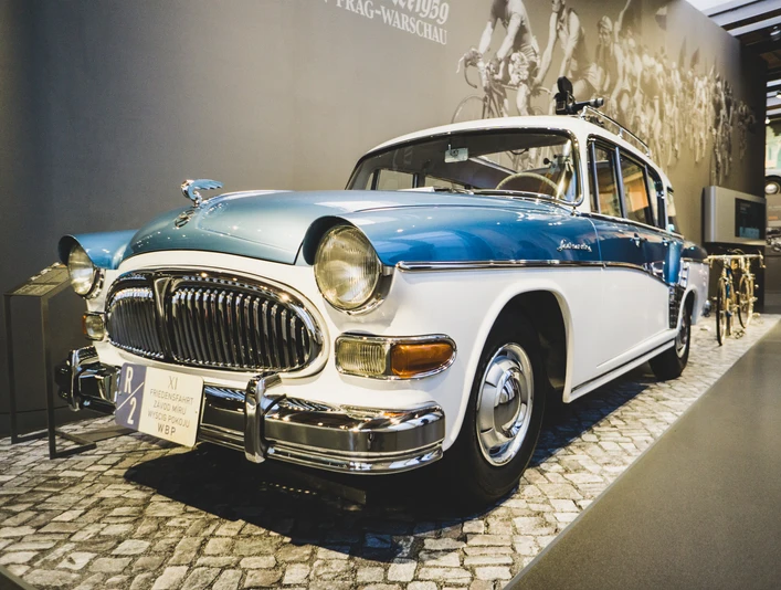August Horch Museum Zwickau - P240 Friedensfahrt Ein historischer blauer und weißer Oldtimer neben Retro-Fahrrädern in einer Museumsausstellung.A historic blue and white vintage car next to retro bicycles in a museum exhibition.Historický modrobílý automobil v muzeu vedle retro jízdních kol.Zabytkowy niebiesko-biały samochód zabytkowy obok rowerów retro na wystawie muzealnej.Een historische blauw-witte oldtimer naast retro fietsen in een museumtentoonstelling.Un'auto d'epoca blu e bianca accanto a biciclette retrò in una mostra museale.