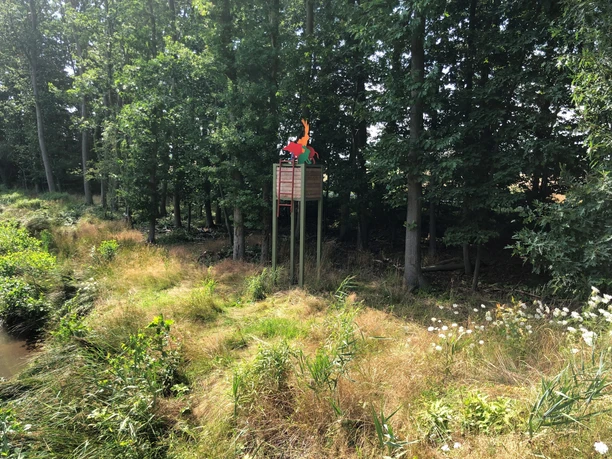 Hochsitz Ein Hochsitz aus Holz steht erhöht im Wald am Waldrand, umgeben von Bäumen und üppigem Gras.