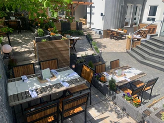 Zum Schwanen Gemütlicher Restaurantgarten mit Holzmöbeln und bunten Blumenbeeten unter schattenspendenden Bäumen.