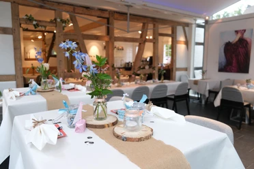 Café Buchmühle Innenbereich Ein stilvoll gedeckter Tisch in einem modernen Restaurant mit Blumenarrangement und Kerzen.