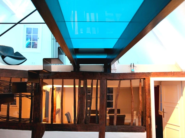 Café Buchmühle Glasdach Modernes Interieur: Treppe und Glassteg mit blauem Licht in einem stilvollen, renovierten Altbau.