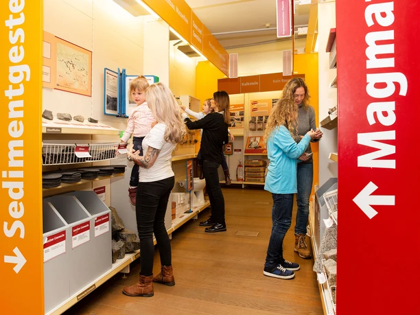 Visitors in a store look at various geological materials on colorful shelves.