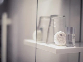 Bierenbacher Hof Ein Badezimmerregal mit zwei Gläsern, einem runden Seifenstück und einer kleinen Shampoo-Flasche.