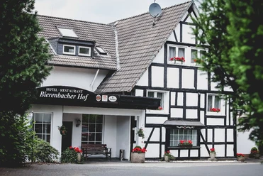 Bierenbacher Hof Ein Fachwerkhaus mit dunklem Holz, weißen Wänden und bunter Blumendekoration im Eingangsbereich.