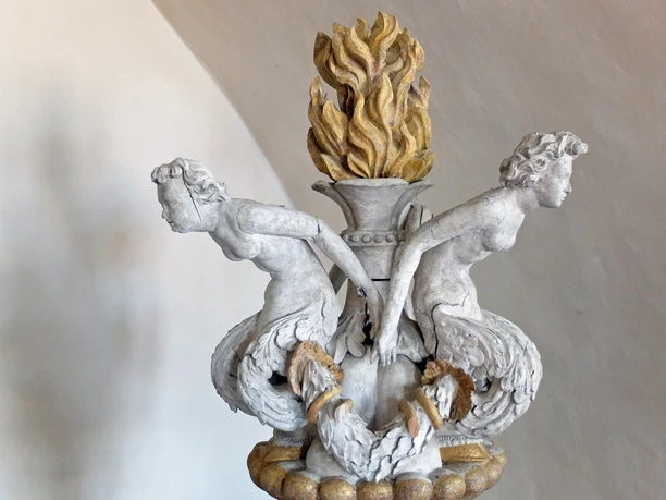 DE_Meissen_Dom_Wolfgang Gärtner_DSCF3028.jpg Zwei steinerne Figuren mit fischähnlichem Unterleib tragen eine flammende Vase.