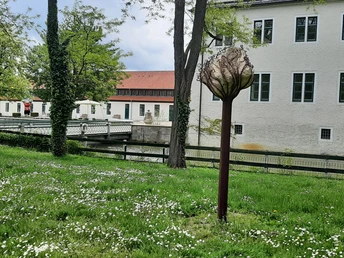 Skulptur im Park des Schlosses Benkhausen, umgeben von grüner Wiese und blühenden Bäumen.