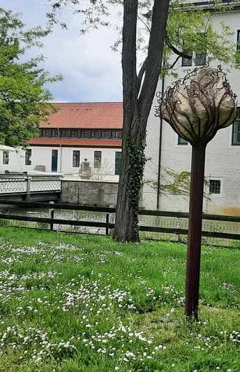 Skulptur im Park des Schlosses Benkhausen, umgeben von grüner Wiese und blühenden Bäumen.