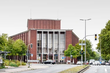 Schauspielhaus Bochum <p>Das Bild zeigt ein modernes Gebäude mit großer Glasfassade an einer belebten Straßenkreuzung.</p>