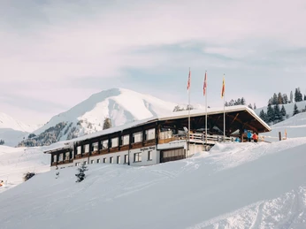 Mountain Hotel Wiriehorn in winter Verschneites Bergasthaus, davor stehen drei FahnenmastenSnow-covered mountain inn with three flagpoles in front of itAuberge de montagne enneigée, devant laquelle se trouvent trois mâts de drapeaux