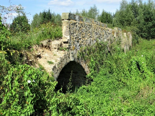 Vierbogenbrücke Herrengraben Steinbrücke mit vier Bögen, umgeben von dichter Vegetation, verbindet historische Wanderwege.