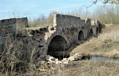 Vierbogenbrücke Herrengraben Historische Steinbrücke mit vier Bögen, umgeben von verwilderter Vegetation und ruhigem Wasserlauf.