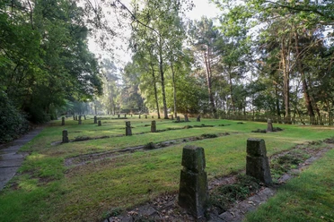 Begräbnisstätte ©Emsland Tourismus Gräberfeld im Grünen mit schlichten Steinen, umgeben von Bäumen und eingezäuntem Waldrand