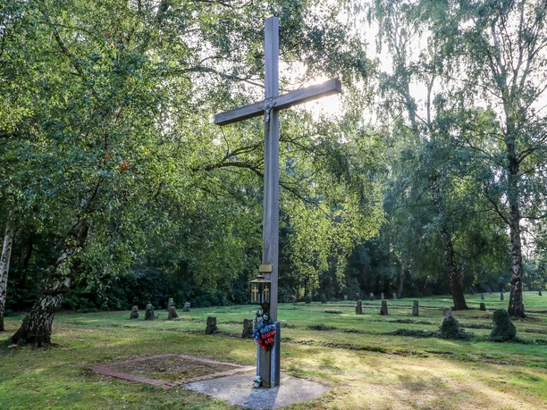 Begräbnisstätte ©Emsland Tourismus Holzkreuz auf einer Wiese mit Grabsteinen, umgeben von alten Birken im Naturpark Hümmling.