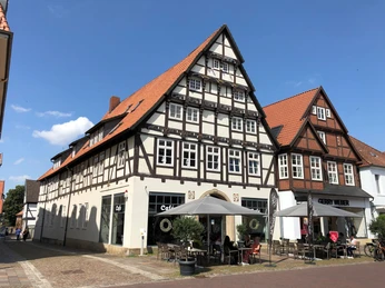 Fachwerkhaus in Bückeburg mit markantem Satteldach und Café im Erdgeschoss bei Sonnenschein.