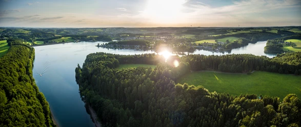 Bevertalsperre Luftaufnahme vom idyllischen Beversee bei Sonnenuntergang in Hückeswagen, umgeben von üppigen Wäldern.