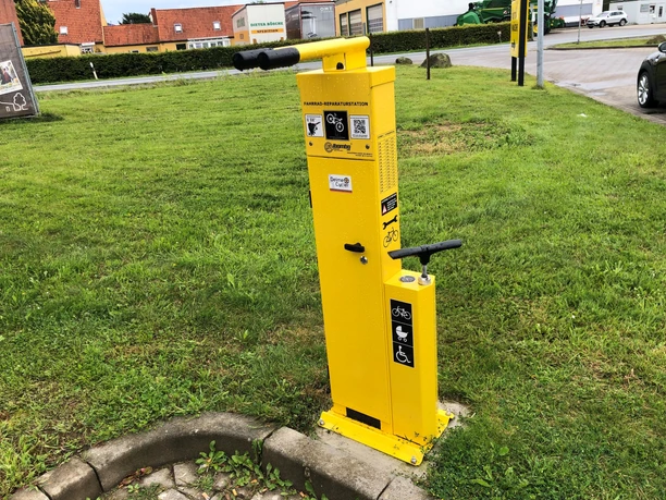 Lufttankstelle Hoya classic Gelbe Luftpumpenstation für Fahrräder auf grünem Rasen in einer städtischen Umgebung.