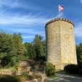Burg Ravensberg in Borgholzhausen Rundturm der Burg Ravensberg in Borgholzhausen, umgeben von Bäumen unter blauem Himmel mit Wolken.