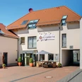 Hotel Elisabeth mit roten Ziegeldächern, begrünten Eingangspflanzen und Sitzbereich im Vordergrund.