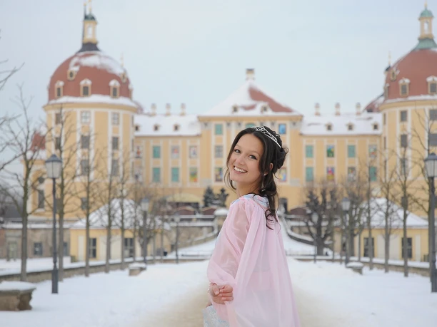 MOR_3HfA_Claudia_Hübschmann_Aschenbroedel_ausst102_2012.verkleinert.jpg Eine Frau im Kostüm vor einem schneebedeckten Schloss im Winter.